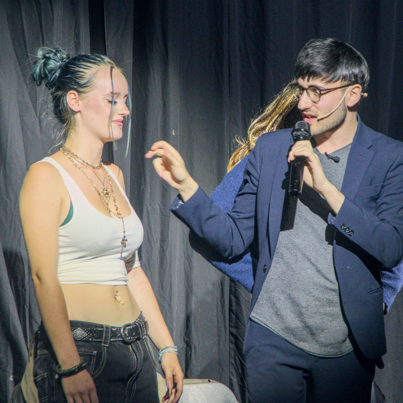 Hypnotist speaking with a seated volunteer during a stage hypnosis routine