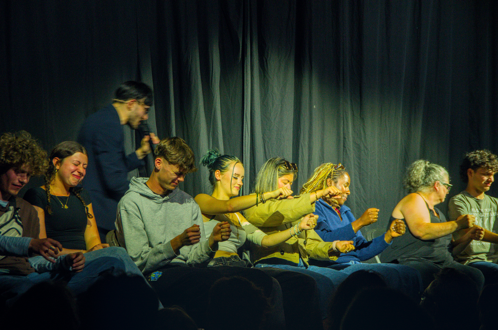 Volunteers seated on stage acting out a driving routine during a hypnosis show