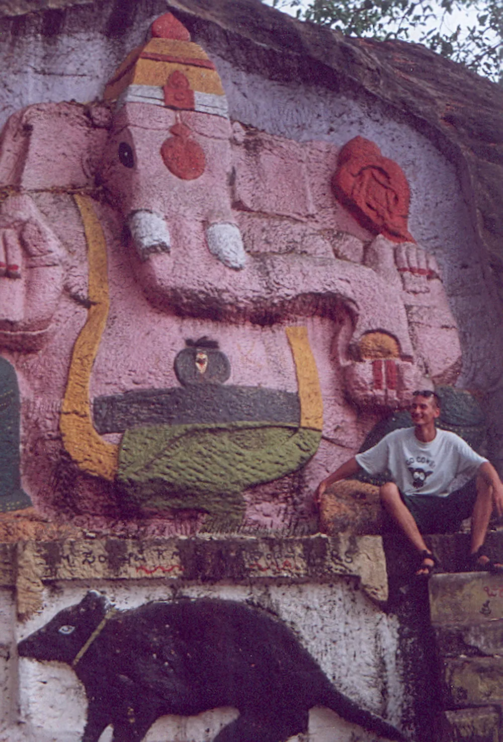Ganesh and a rat on a wall beside a seated traveller